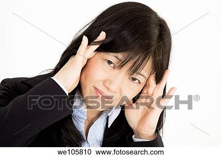 Stock Image - Beautiful Asian Businesswoman with a stress related headache on a white background. Fotosearch