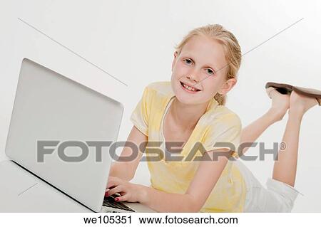 Child laying on a white background working on laptop computer View Large Photo Image Stock Image - Child laying on a white background working on laptop computer. Fotosearch