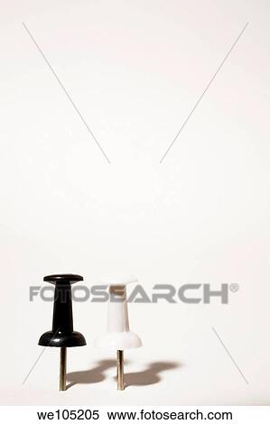 Stock Photography - Close-up of Two upright Black and White Push Pins on a White Background, Studio Composition. Fotosearch
