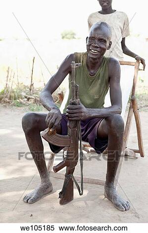 Stock Photography - Dinka man cleaning ak-47 in Lilir Sudan, December 2010. Fotosearch