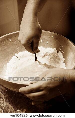 Stock Photography - Hands holding a bowl and stirring flour into the batter. Fotosearch