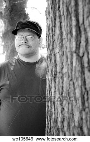 Hispanic man standing next to a tree View Large Photo Image Stock Photograph - Hispanic man standing next to a tree. Fotosearch
