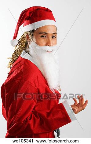 Stock Image - Man with dreadlocks dressed as Santa Claus with his hand out. Fotosearch