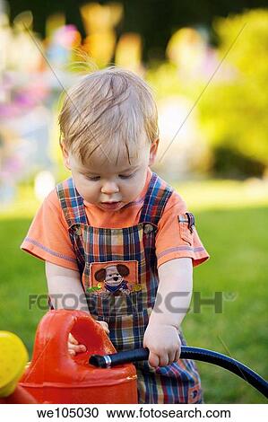 Portrait of a toddler playing with garden hose and watering can in the garden View Large Photo Image Stock Image - Portrait of a toddler playing with garden hose and watering can in the garden. Fotosearch