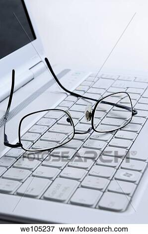 Reading glasses resting on the white keyboard of an open laptop computer View Large Photo Image Stock Photo - Reading glasses resting on the white keyboard of an open laptop computer. Fotosearch