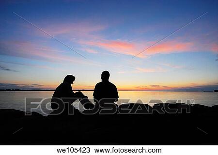Silhouette of a couple by a lake at sunset, Sweden View Large Photo Image Stock Image - Silhouette of a couple by a lake at sunset, Sweden. Fotosearch