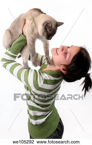Smiling young girl lifting a Siamese cat to her face on a white background View Large Photo Image Stock Image - Smiling young girl lifting a Siamese cat to her face on a white background. Fotosearch