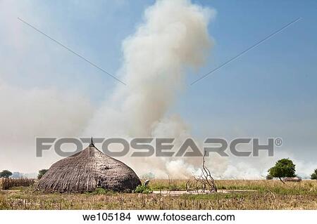Picture - The village of Lilir Sudan with grassfire in background, December 2010. Fotosearch