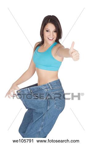 Stock Image - Woman showing weight loss by wearing an old pair of jeans. Fotosearch