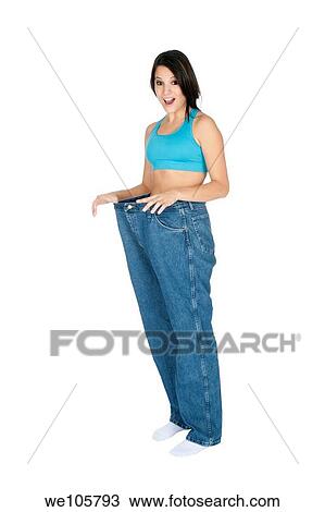 Stock Image - Woman showing weight loss by wearing an old pair of jeans. Fotosearch