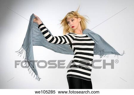 Young blond woman in striped top holding a scarf in the wind on gray background View Large Photo Image Stock Photography - Young blond woman in striped top holding a scarf in the wind on gray background. Fotosearch