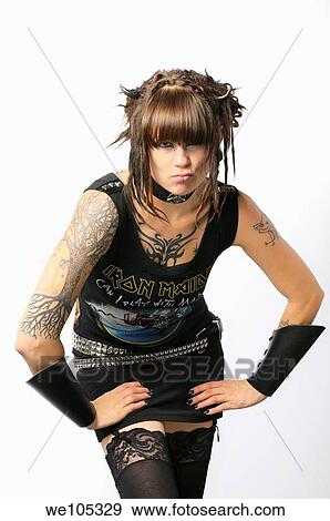 Stock Photo - Young pouting heavy metal lady with horns piercings and tattoos on a white background. Fotosearch
