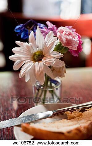 A small vase of flowers and a piece of bread on a table in a restaurant View Large Photo Image Stock Image - A small vase of flowers and a piece of bread on a table in a restaurant. Fotosearch