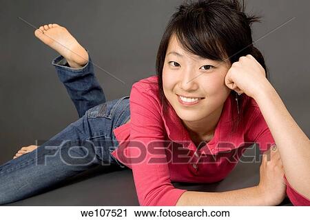Stock Image - Asian Teenage girl posing on gray background with some attitude. Fotosearch