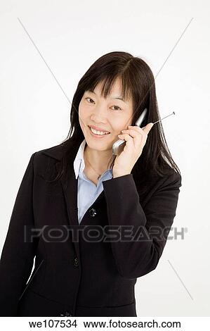 Beautiful Asain Businesswoman talking on a cell phone on a white background View Large Photo Image Picture - Beautiful Asain Businesswoman talking on a cell phone on a white background. Fotosearch