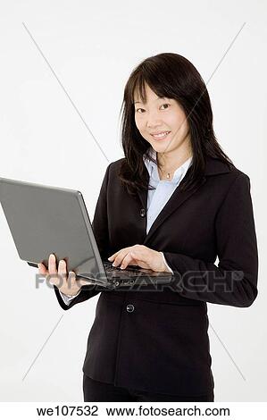 Beautiful Asian Businesswoman posing on a white background holding a laptop computer View Large Photo Image Stock Image - Beautiful Asian Businesswoman posing on a white background holding a laptop computer. Fotosearch
