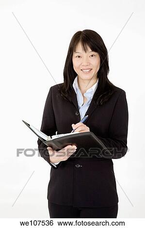 Stock Photograph - Beautiful Asian Businesswoman working with a day planner on a white background. Fotosearch