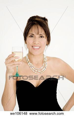Beautiful Brazilian or Hispanic holding a glass of white wine in a black evening gown on a white background View Large Photo Image Stock Photo - Beautiful Brazilian or Hispanic holding a glass of white wine in a black evening gown on a white background. Fotosearch