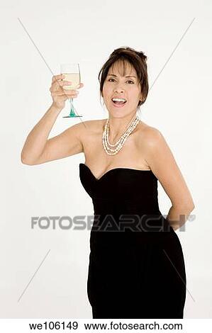 Beautiful Brazilian or Hispanic holding a glass of white wine in a black evening gown on a white background View Large Photo Image Stock Photo - Beautiful Brazilian or Hispanic holding a glass of white wine in a black evening gown on a white background. Fotosearch