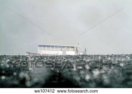 Stock Image - Blue dhoni boat sailing through heavy rain off the coast of Rasdhoo, an uninhabited island in the Maldives. Fotosearch
