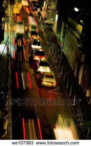 Stock Image - Cars travelling along a street during a rainy night. Fotosearch
