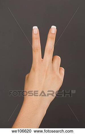 Stock Image - Caucasian female using hand gestures to show two fingers. Fotosearch