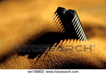 Stock Image - Computer chip half-buried in sand. Fotosearch
