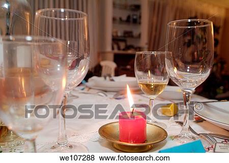 Stock Photo - Empty wineglasses on a Christmas table dressed with a burning candle. Fotosearch