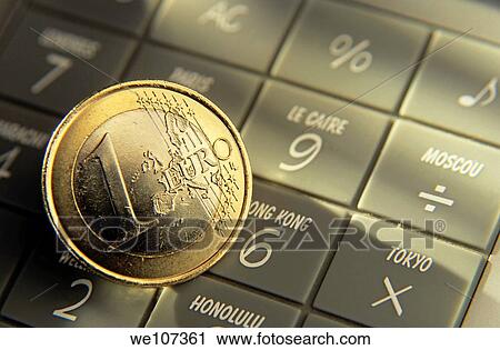 Stock Image - One Euro coin on top of a calculator. Fotosearch