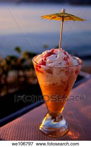 Stock Photo - Peach ice cream sundae served with a cocktail umbrella in a glass. Fotosearch