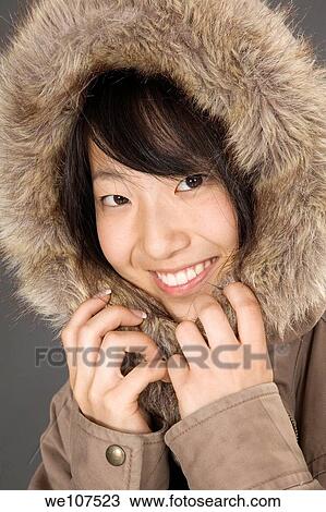 Stock Image - Portrait of a beautiful Asian teenager in a hooded coat. Fotosearch