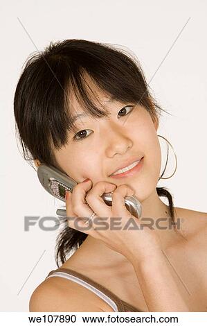 Portrait of a beautiful Asian teenager talking on a cell phone on a white background View Large Photo Image Stock Image - Portrait of a beautiful Asian teenager talking on a cell phone on a white background. Fotosearch