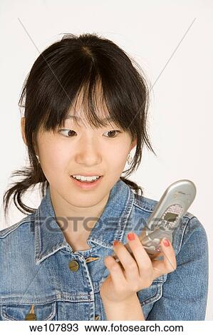 Portrait of a beautiful Asian teenager talking on a cell phone on a white background View Large Photo Image Stock Image - Portrait of a beautiful Asian teenager talking on a cell phone on a white background. Fotosearch