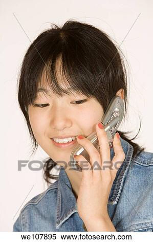 Portrait of a beautiful Asian teenager talking on a cell phone on a white background View Large Photo Image Stock Photography - Portrait of a beautiful Asian teenager talking on a cell phone on a white background. Fotosearch