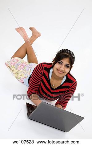 Stock Photo - Portrait of Indian teenager working with a laptop conputer on a white background. Fotosearch