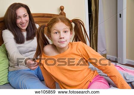 Stock Photo - Preteen redhead girl and her mother sitting in bed. Fotosearch