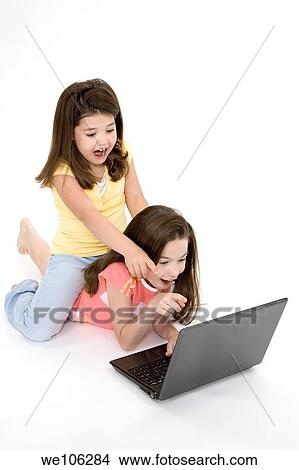 Sisters playing on a laptop computer on a white background View Large Photo Image Picture - Sisters playing on a laptop computer on a white background. Fotosearch