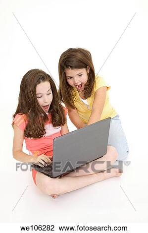 Sisters playing on a laptop computer on a white background View Large Photo Image Stock Image - Sisters playing on a laptop computer on a white background. Fotosearch