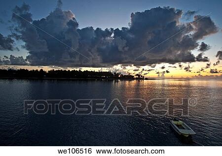 Sun rising over a silhouetted island in a sky filled with heavy storm clouds, Maldives View Large Photo Image Stock Photograph - Sun rising over a silhouetted island in a sky filled with heavy storm clouds, Maldives. Fotosearch