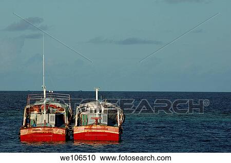 Two red fishing boats moored side by side in the blue ocean, Maldives View Large Photo Image Stock Image - Two red fishing boats moored side by side in the blue ocean, Maldives. Fotosearch