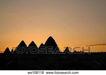 Stock Photo - View of silhouetted rock-cut cave dwellings in Goreme after sunset, Cappadocia region, Turkey. Fotosearch
