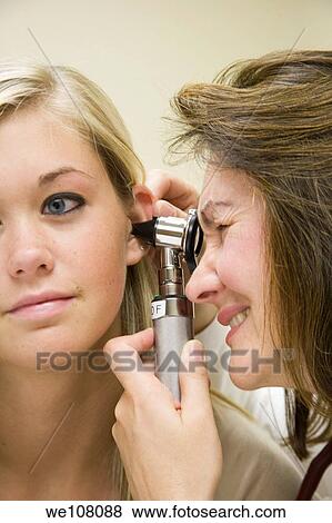 Stock Photo - A doctor examining a teenage female patient with an ear scope. Fotosearch
