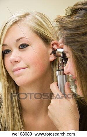 A doctor examining a teenage female patient with an ear scope View Large Photo Image Stock Photo - A doctor examining a teenage female patient with an ear scope. Fotosearch