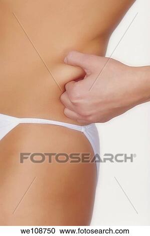 Stock Image - A woman testing how much fat she has using the? Pinch an inch? method. Fotosearch