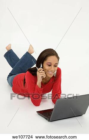 African American teen working on laptop computer and talking ona cell phone View Large Photo Image Picture - African American teen working on laptop computer and talking ona cell phone. Fotosearch