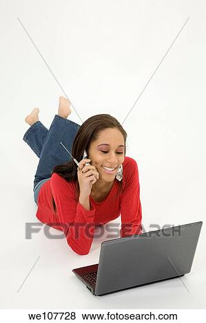 African American teen working on laptop computer and talking ona cell phone View Large Photo Image Stock Photo - African American teen working on laptop computer and talking ona cell phone. Fotosearch