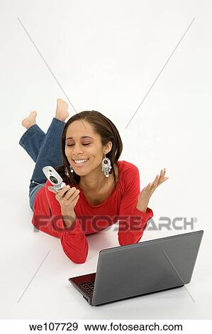 Stock Photo - African American teen working on laptop computer and talking ona cell phone. Fotosearch