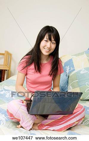 Stock Photo - Asian American teen working on laptop computer. Fotosearch
