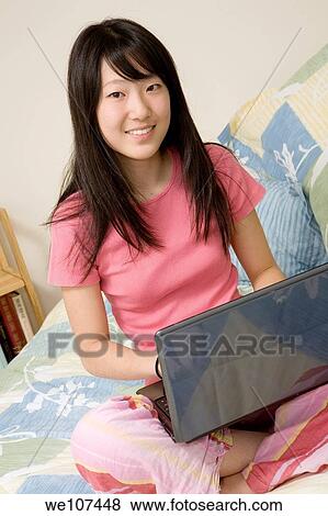 Asian American teen working on laptop computer View Large Photo Image Stock Photo - Asian American teen working on laptop computer. Fotosearch