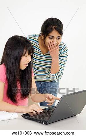Stock Image - Asian and East Indian teenagers looking surprised by what they found on the laptop computer. Fotosearch